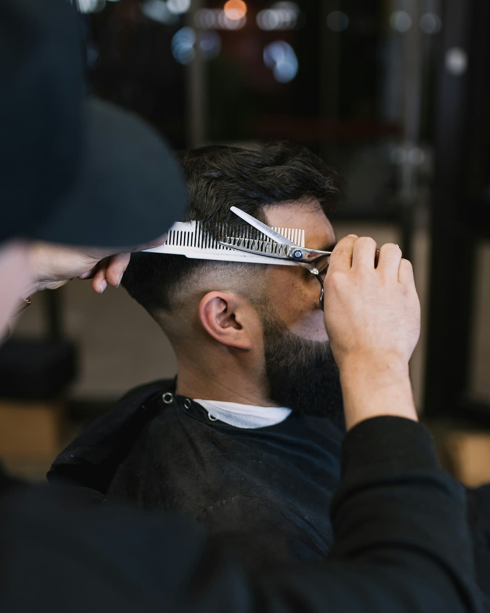 Barbeiro cortando o cabelo de um cliente com tesoura